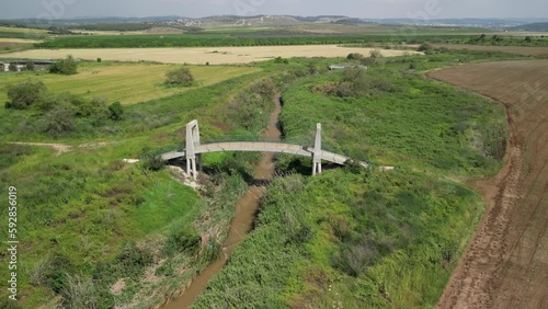 Aerial view of a small bridge over a creek surrounded by green fields