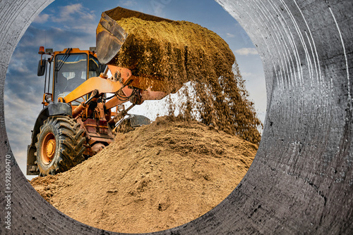 Powerful wheel loader or bulldozer working on a quarry or construction site. Loader with a full bucket of sand. Powerful modern equipment for earthworks.