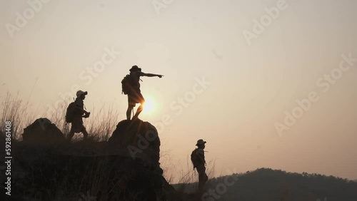 Silhouette Three  scout schoolboy hiking with backpack standing on a cliff Boy scouts look through binoculars exploring a beautiful forest in the evening as the sun sets. photo