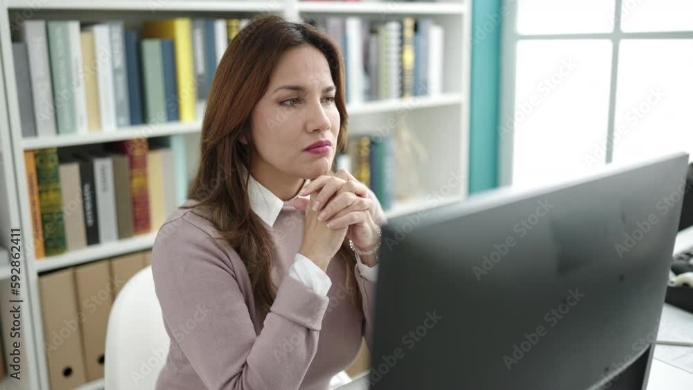 Young beautiful hispanic woman student using computer with doubt expression at library university Young beautiful hispanic woman student using computer with doubt expression at library university