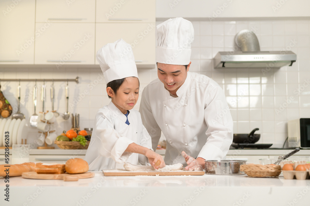 Young Asian father and his son wearing chef uniform baking together in kitchen at home Young Asian father and his son wearing chef uniform baking together in kitchen at home