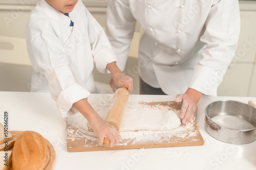 Young Asian father and his son wearing chef uniform baking together in kitchen at home