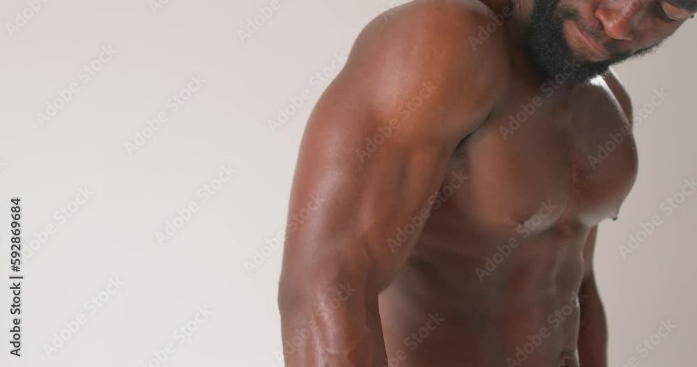 Confident young nude strong African man training with dumb-bells against white background. close up cropped video. slow motion. man holding dumbbell black man doing cross fit workout, training