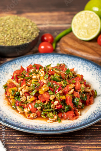 Gavurdagi salad. Walnut salad on wood background. Healthy salad prepared with tomatoes, peppers, cucumbers, onions, pomegranate syrup, olive oil and walnuts. Close up