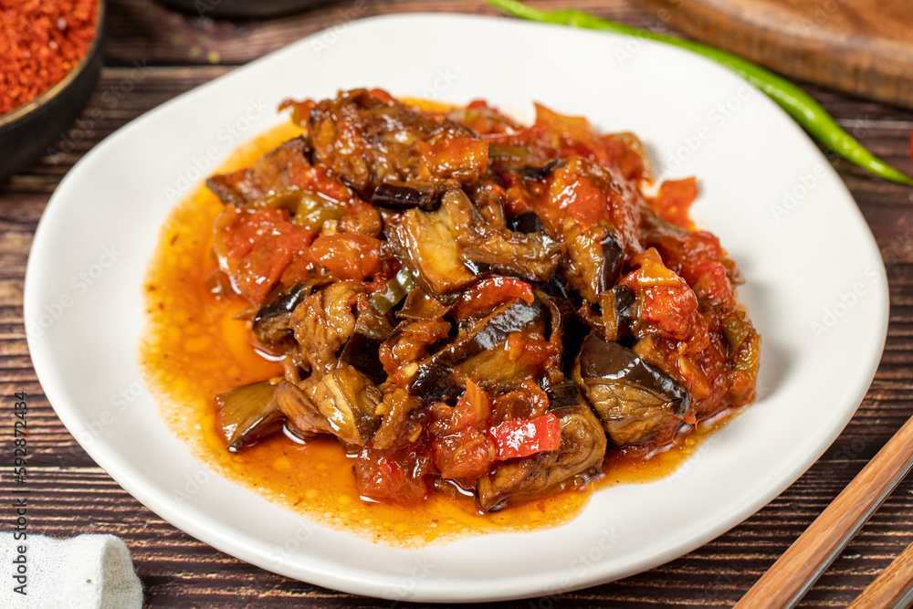 Eggplant dish with vegetables fried in olive oil on a wooden floor. Close up Eggplant dish with vegetables fried in olive oil on a wooden floor. Close up