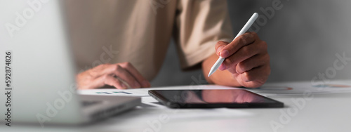 Close up of student hand using electronic pen with tablet. education e-learning concept for banner