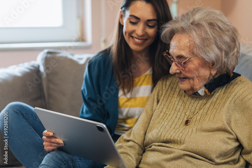 Nurse visiting a senior woman, showing her news online. photo