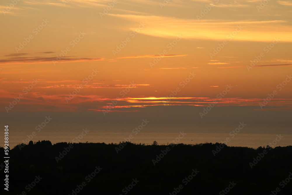 能登の風景。雲がオレンジに染まる夕暮れの空。