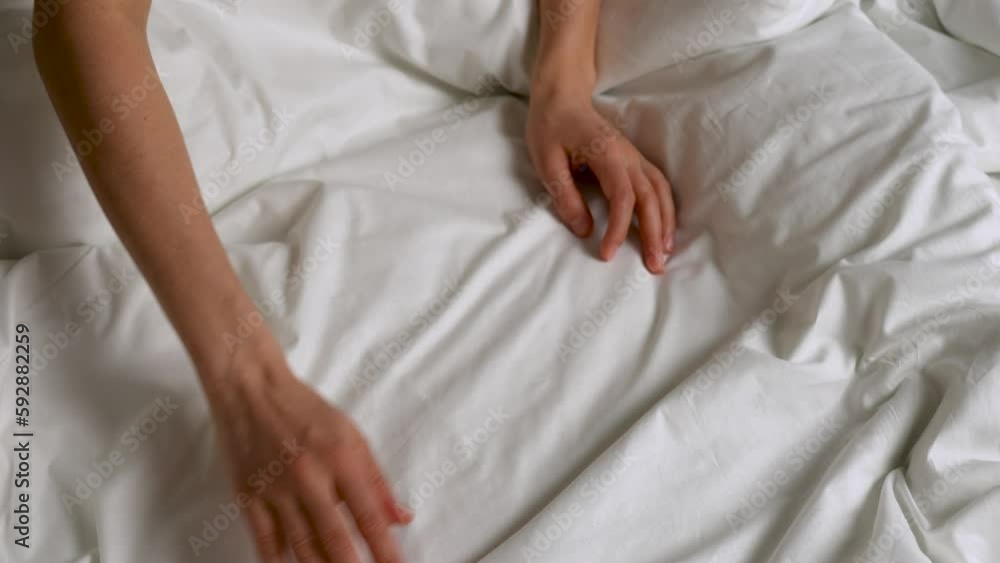 Close Up of female hand touching soft white sheet Close Up of female hand touching soft white sheet