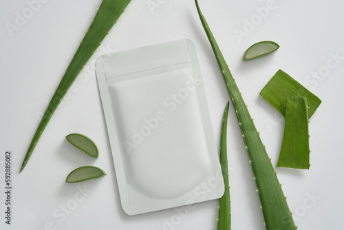 Top view of facial sheet mask packaging mockup and fresh aloe vera decorated on white background. Aloe vera extract makes a mask that whitens, moisturizes and prevents aging