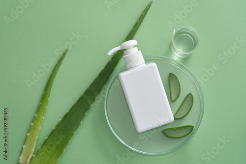Petri dish with Aloe vera slices and unlabeled pump bottle put on, a beaker of Aloe vera gel. Shampoo, cleanser, conditioner cosmetics packaging mockup of Aloe vera (Aloe barbadensis miller) extract