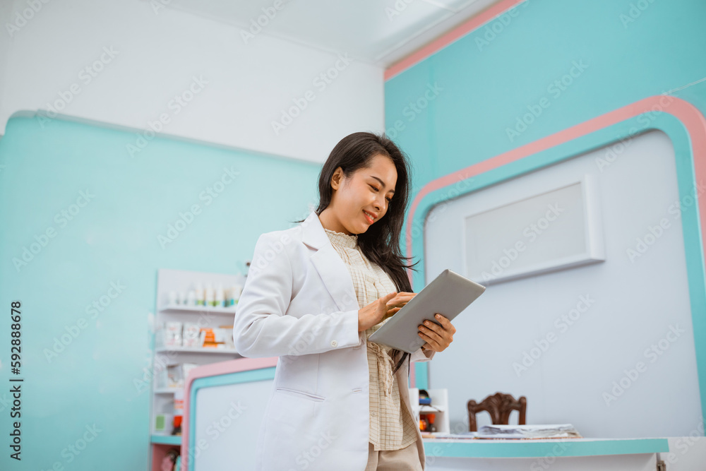 female vet look for information on her tablet standing in front of the receptionist desk female vet look for information on her tablet standing in front of the receptionist desk