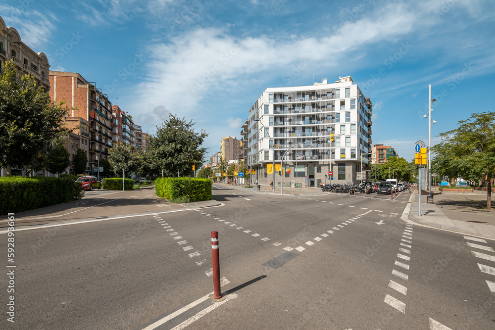 Crossroads on an unoccupied roadway on backdrop of high-rise comfortable houses in new modern area of a European city on a sunny warm summer day. Concept of a convenient urban space