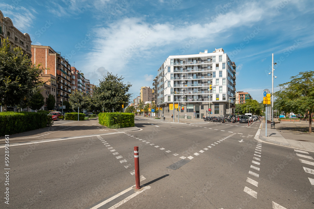 Crossroads on an unoccupied roadway on backdrop of high-rise comfortable houses in new modern area of a European city on a sunny warm summer day. Concept of a convenient urban space Crossroads on an unoccupied roadway on backdrop of high-rise comfortable houses in new modern area of a European city on a sunny warm summer day. Concept of a convenient urban space