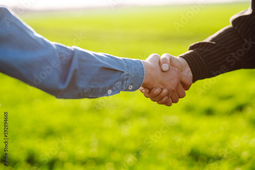 Negotiation. Two farmers agree by shaking hands in a green wheat field. The concept of agricultural business.