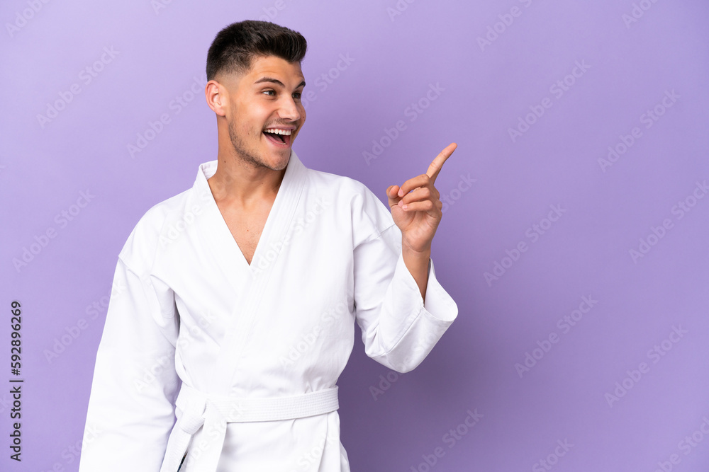 Young caucasian man doing karate isolated on purple background intending to realizes the solution while lifting a finger up Young caucasian man doing karate isolated on purple background intending to realizes the solution while lifting a finger up
