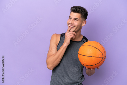 young caucasian woman basketball player man isolated on purple background looking up while smiling