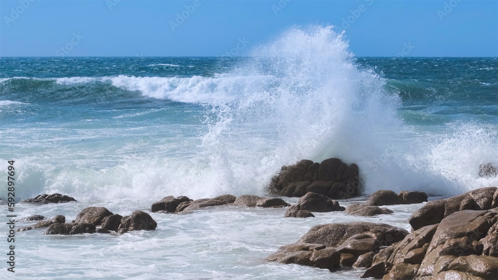 Powerful wave splashing against rocks on the Atlantic coast of Portugal in summer, sending spray  high into the air
