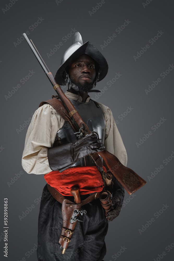 Shot of 18th century soldier with rifle dressed in armor against grey background. Shot of 18th century soldier with rifle dressed in armor against grey background.