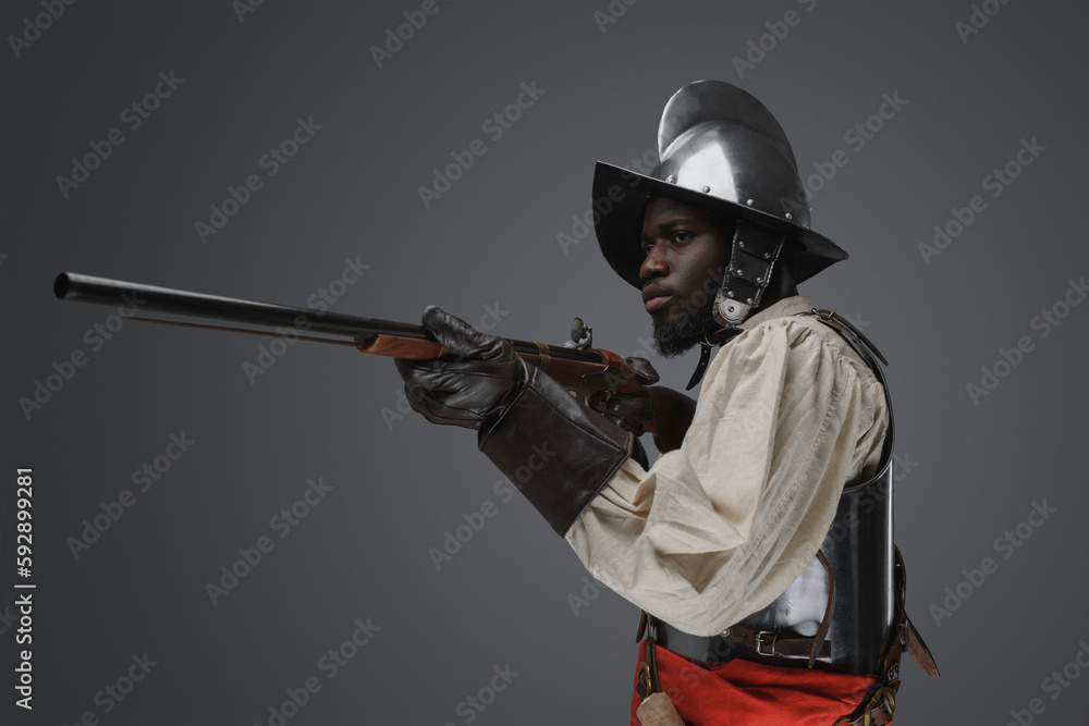 Shot of medieval soldier dressed in steel armor and helmet aiming flintlock musket. Shot of medieval soldier dressed in steel armor and helmet aiming flintlock musket.