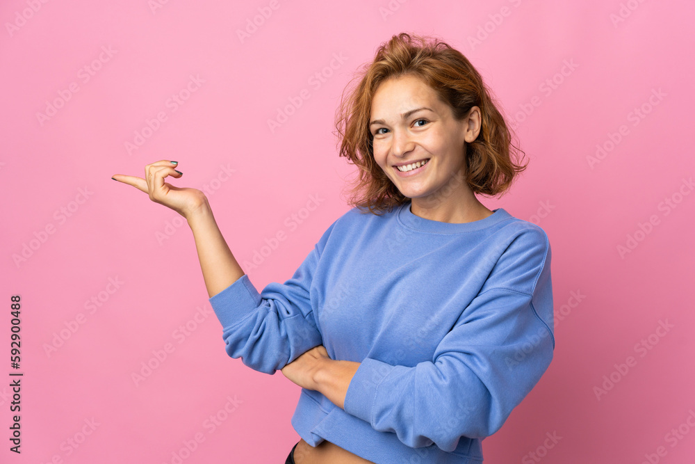 Young Georgian woman isolated on pink background pointing finger to the side Young Georgian woman isolated on pink background pointing finger to the side