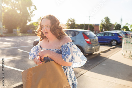 Teenager with down syndrome in community shopping with brown paper bag photo