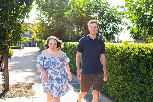 Happy girl with down syndrome talking to provider as they walk around the streets photo