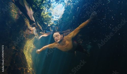 Wallpaper Mural Man dives in the freshwater river with sunny rays shining through the water Torontodigital.ca