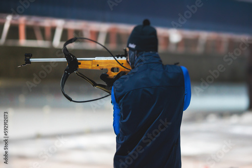 Biathlete with rifle on a shooting range during biathlon training, skiers on training ground in winter snow, athletes participate in biathlon competition on slope piste