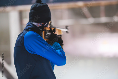 Biathlete with rifle on a shooting range during biathlon training, skiers on training ground in winter snow, athletes participate in biathlon competition on slope piste