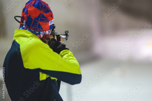 Biathlete with rifle on a shooting range during biathlon training, skiers on training ground in winter snow, athletes participate in biathlon competition on slope piste photo