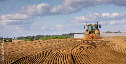 Obraz na plátně Agriculteur au volant de son tracteur labourant son champ de terre dans la campagne en France
