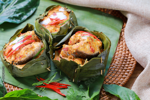 Fototapeta Traditional Steamed snakehead fish with curry paste and tahitian noni leaf inside