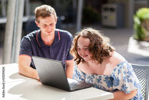 happy young lady with down syndrome working on laptop getting assistance with personal activities