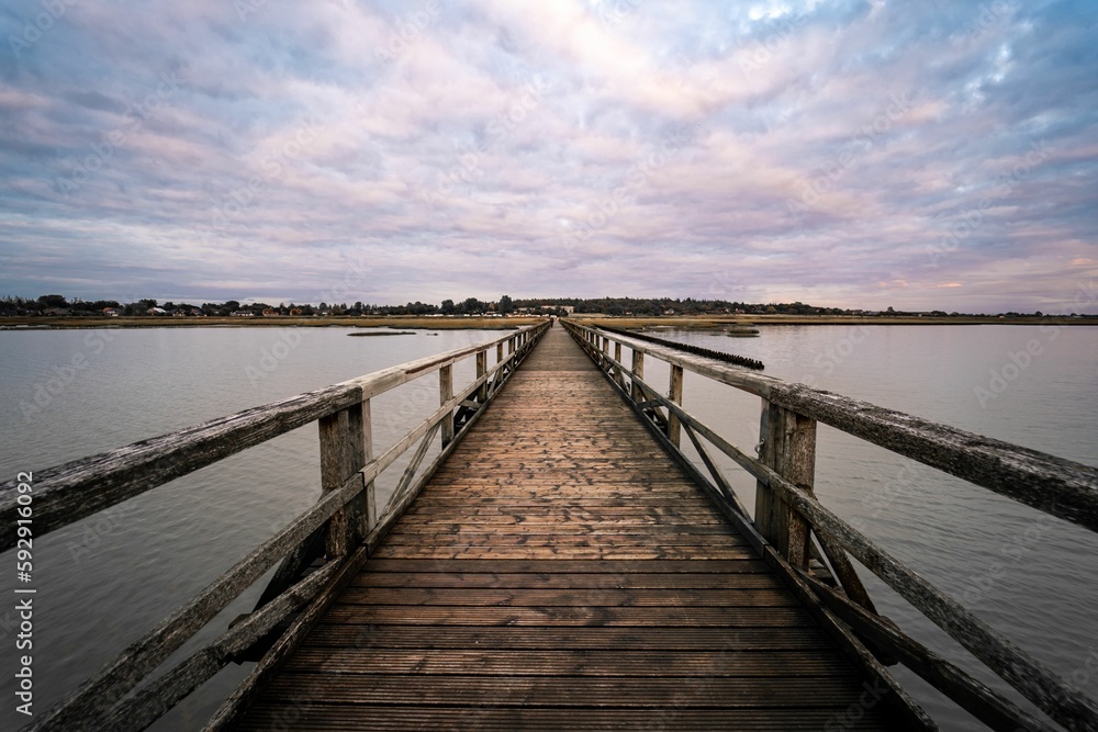 Old wooden bridge over the river under a cloudy sky