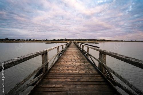 Old wooden bridge over the river under a cloudy sky