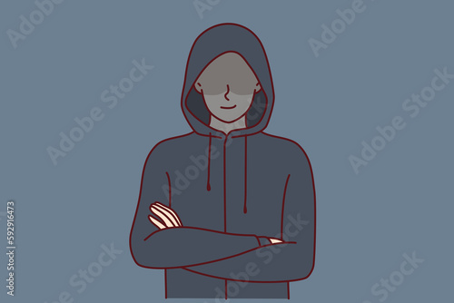 Anonymous man stands with arms crossed and hiding eyes behind hood for concept of secret surveillance or banditry. Anonymous guy hiding face wanting to remain incognito planning illegal activities 