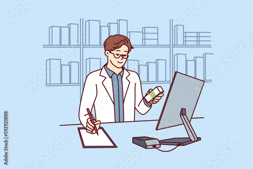 Man pharmacist in white medical coat stands behind counter in pharmacy and prescribes prescription drugs to patients. Pharmacy employee makes notes in notebook choosing antibiotics or vitamins 