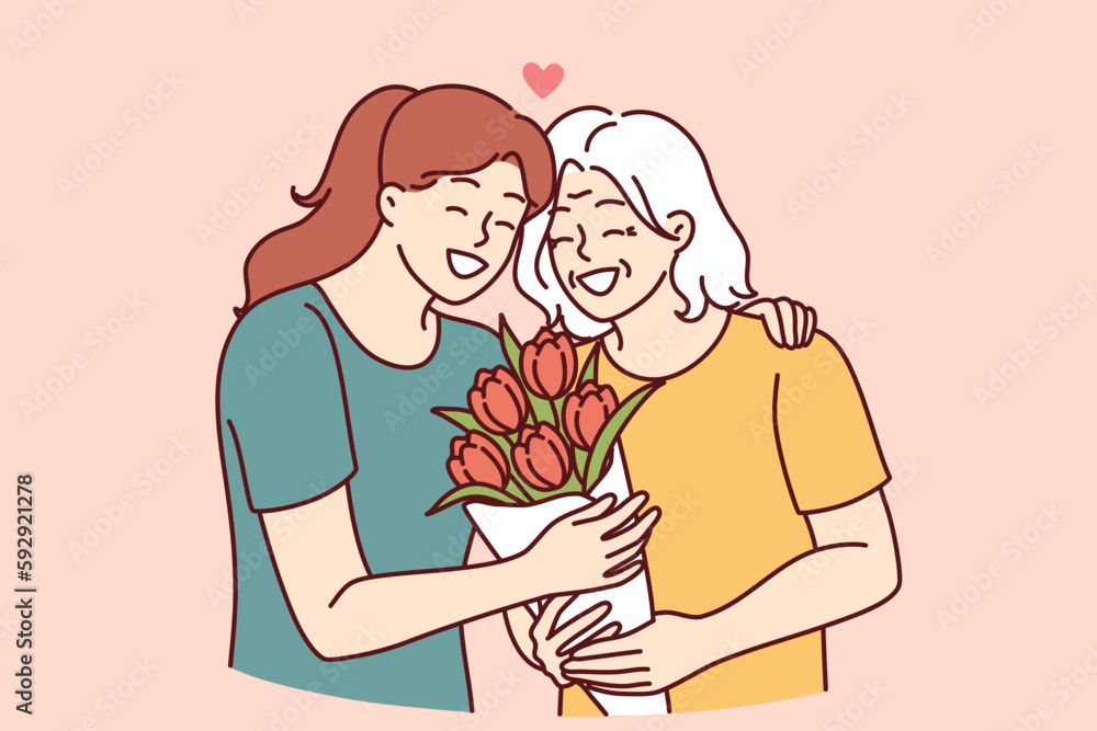 Φωτογραφία Woman hugs elderly mother and gives bouquet of flowers congratulating with birthday or mother day and thanks for good upbringing