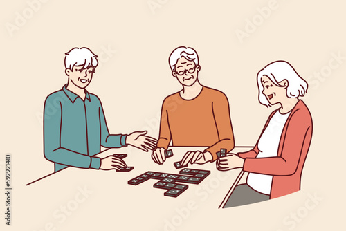 Elderly people play dominoes undergoing rehab at nursing home or having sunday get-together with friends. Men and women are sitting at table enjoying game of dominoes with former colleagues 