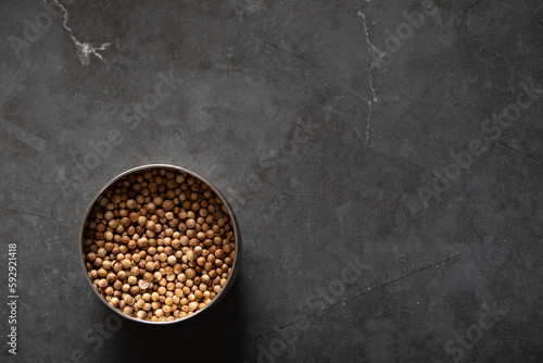 Spice tin of coriander seeds on dark marble background photo