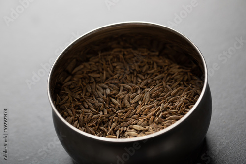 Spice tin of cumin seeds on dark marble background photo