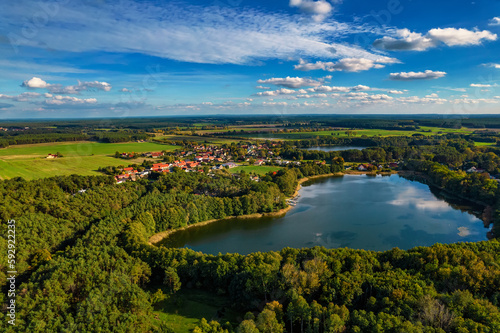 Fototapeta Naklejka Na Ścianę i Meble -  Aerial shot of beautiful lake surrounded by forest in a calm autumn day. Germany.