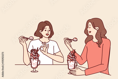Women having lunch sitting in restaurant eating milkshake and discussing personal lives or plans for weekend. Girlfriends eat ice cream or milkshake in cafe wanting to cool off in hot summer weather