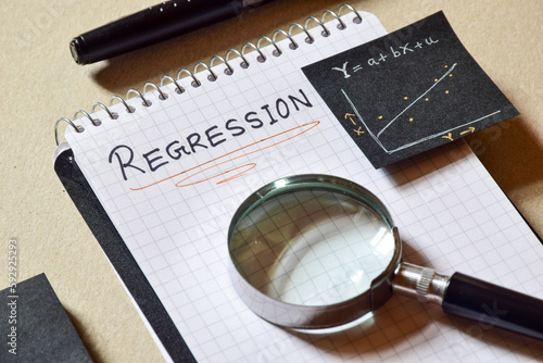 Notepad with the text Regression and it's formula and analysis graph on desk. 