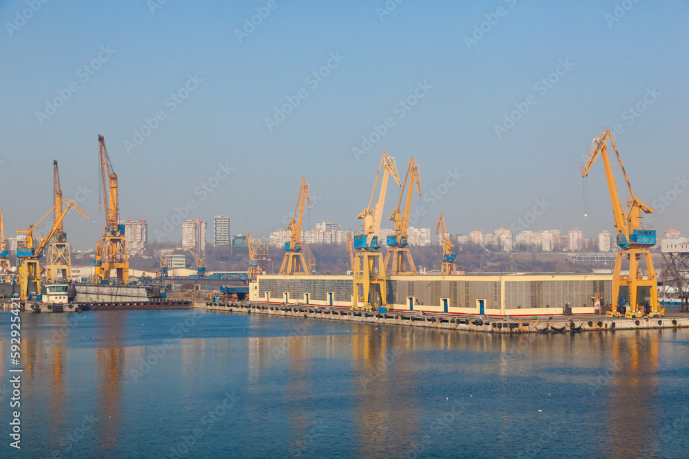 Port cranes on the territory of the seaport in Constanta Romania with blue sky. Territory of the seaport with cranes. Port cranes on the territory of the seaport in Constanta Romania with blue sky. Territory of the seaport with cranes.