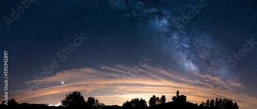 Scenic panoramic view of the silhouettes of a Sanctuary and trees under the starry night sky photo
