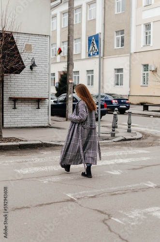 a girl in a coat crosses the road
