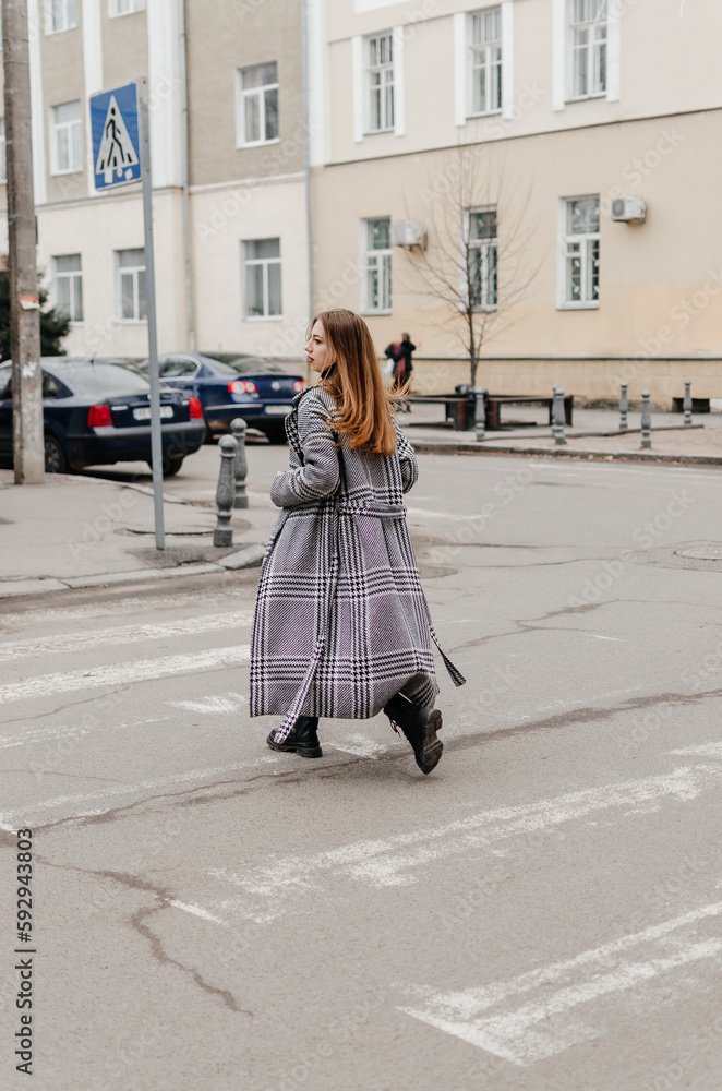 a girl in a coat crosses the road