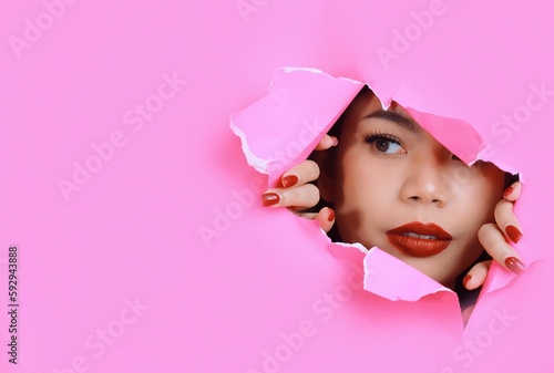 Portrait of beautiful Asian a woman with makeup standing behind pink paper background, copy space.
